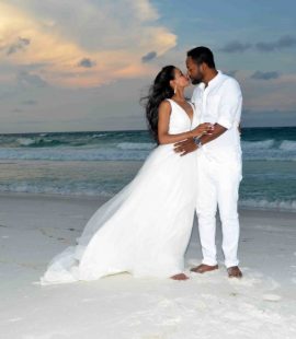 A newly married couple embracing on the beach.