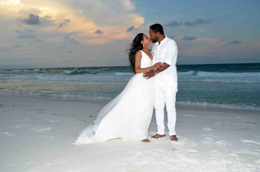 A newly married couple embracing on the beach.