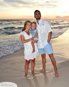 A family standing on the beach with the sunset behind them.