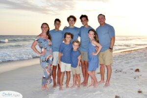 A family standing on the beach with the sunset behind them