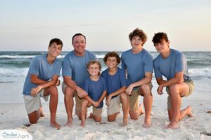 A father and his sons kneeling on the beach