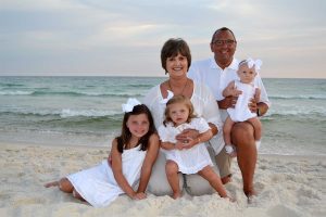 adults and kids in a beach photo with waves behind them