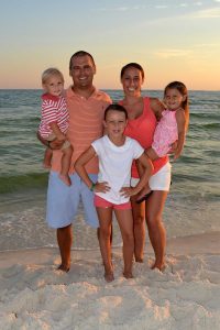 family standing in sand at the beach