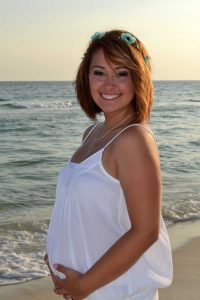 woman smiling in maternity photo at beach