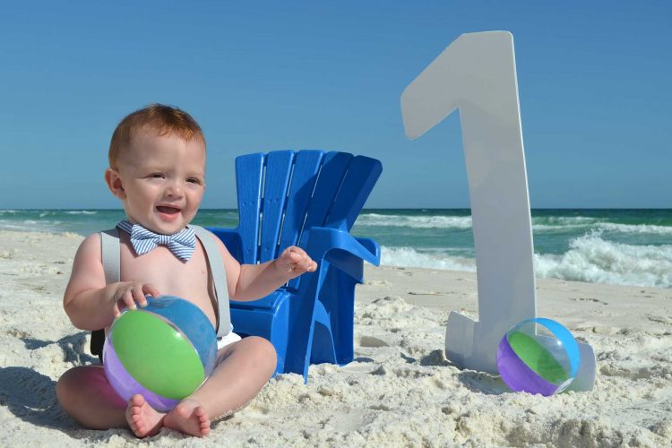 Little boy getting his birthday photo on the beach with a number 1