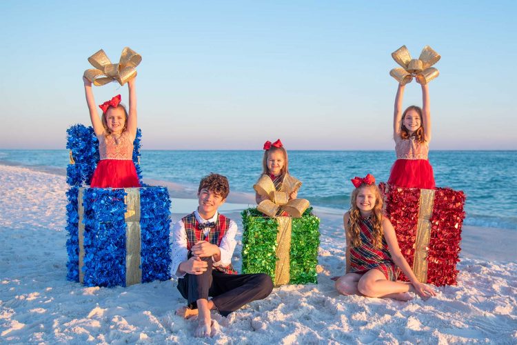 kids posing with holiday presents for their beach photos