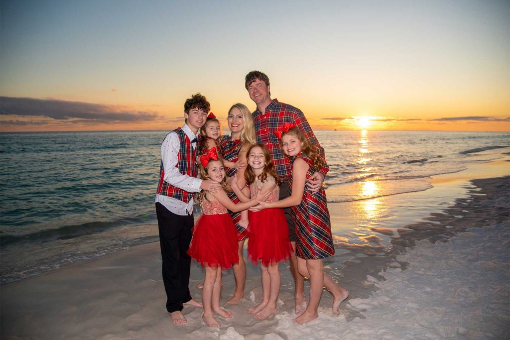 Family dressed in holiday outfits for their sunset beach photo