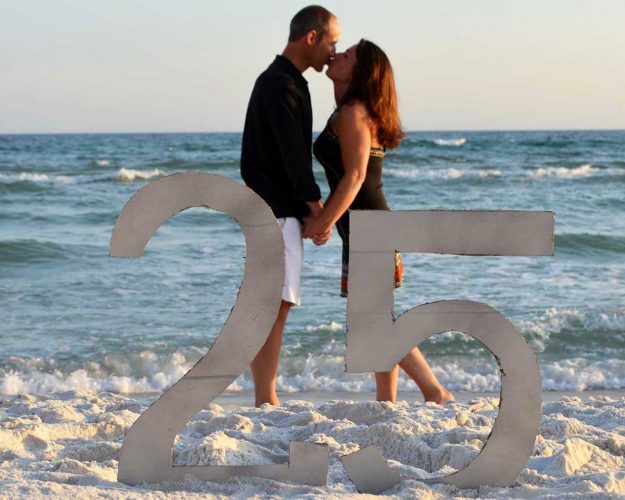 couple kissing with a 25 anniversay sign in front of them on Panama City Beach.