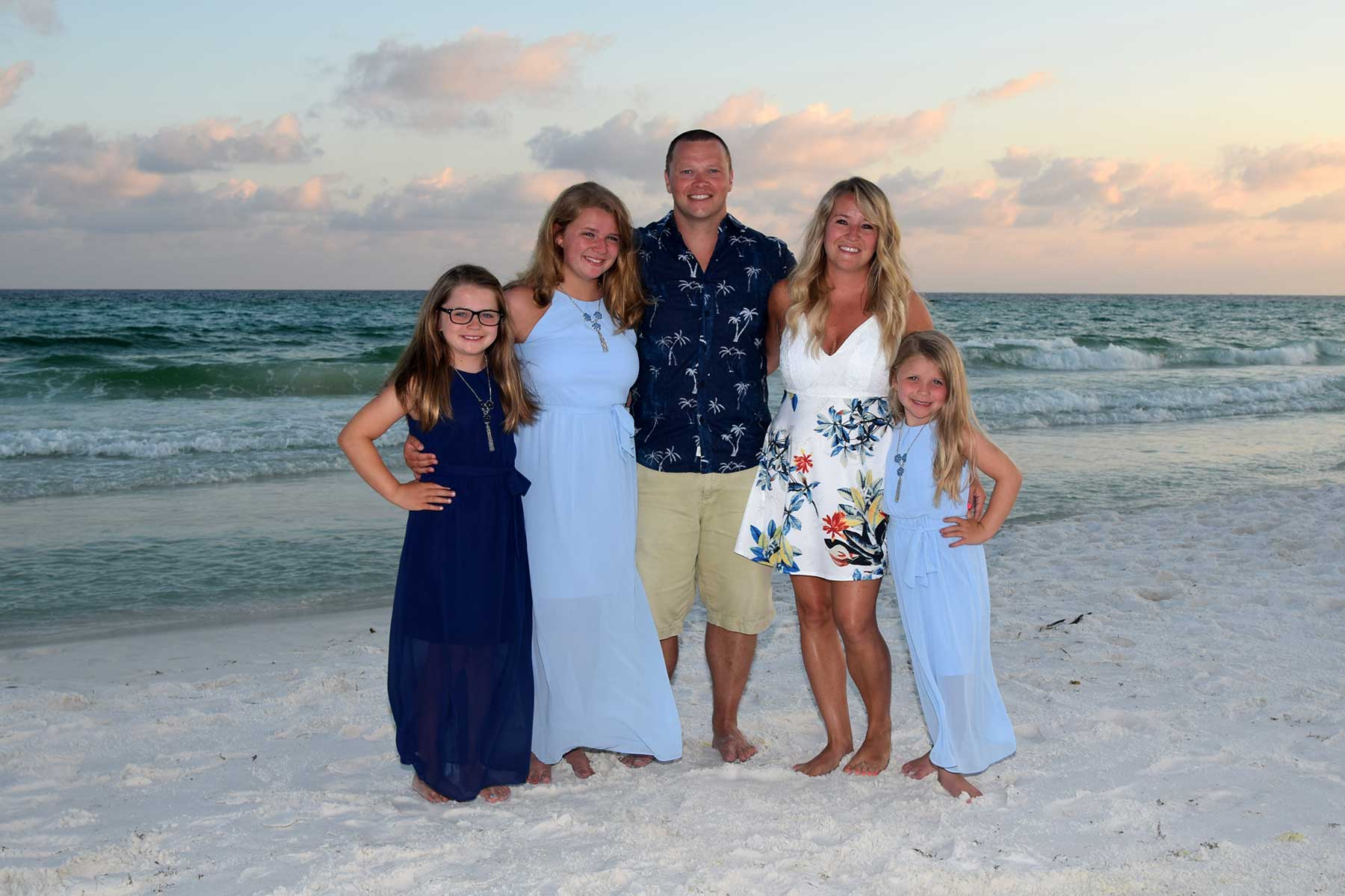 smiling family on Panama City Beach, FL, with waves in the background