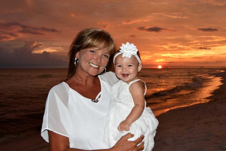 Woman with baby in front of beautiful sunset. We also take sunset photos in Destin, Fort Walton Beach, and Miramar Beach, FL.