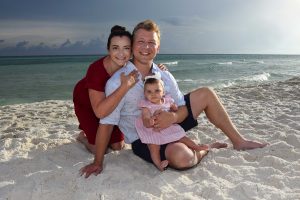 Beach photo taken at sunset of a small, happy family