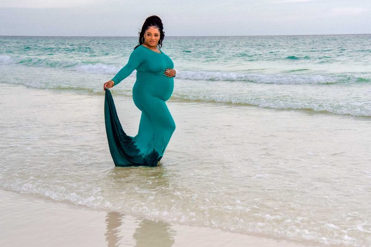 Woman in water at beach hand on pregnant belly