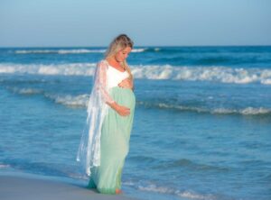 Woman walking through the water in Panama City Beach in her sunset maternity photo.