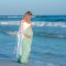woman walking through the water in her sunset maternity photo