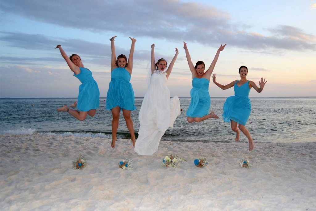 Bride and bridesmaids jumping in the air on the beach