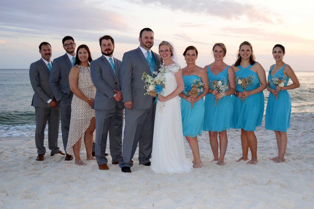 A wedding party on the beach at sunset.