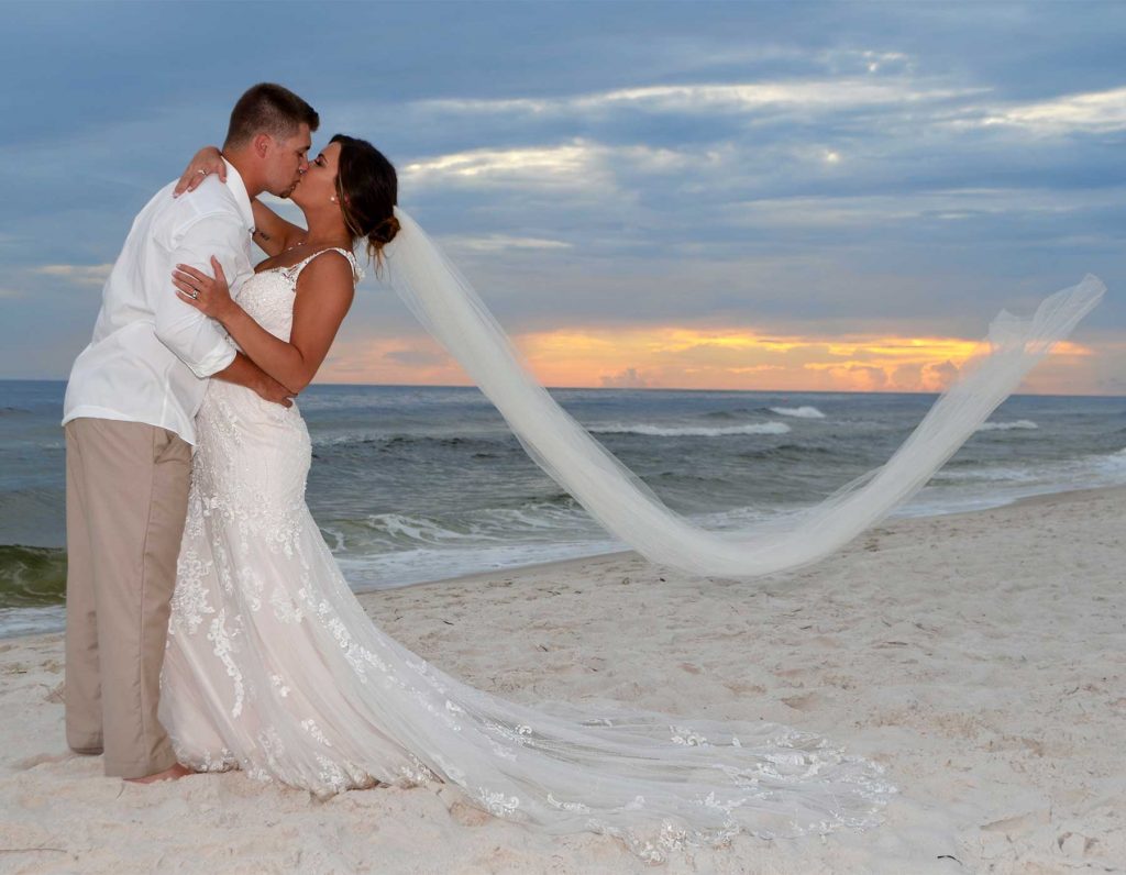 Our Panama City Beach wedding photographer captured this beautiful sunset wedding photo just as the breeze caught the bride's veil