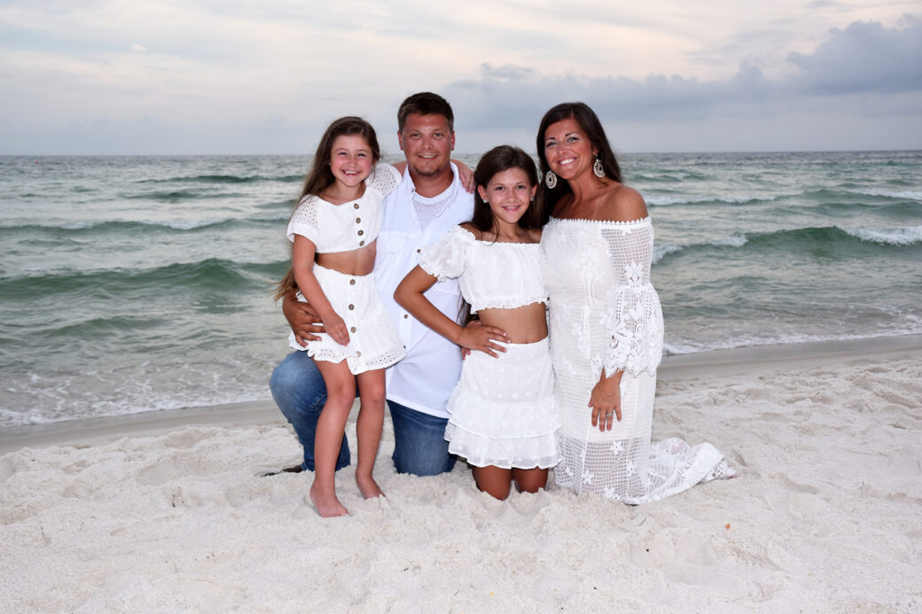 family kneeling in sand for their photo