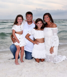 family kneeling in sand for their photo