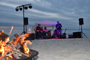 Beach bonfire with musicians in the background