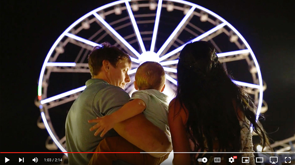 Young family in front of sky wheel. Hire event photographers in Panama City Beach, Florida.