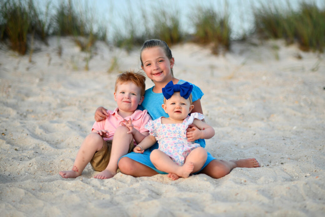 Siblings near dunes in Panama City Beach smile for our photographer.