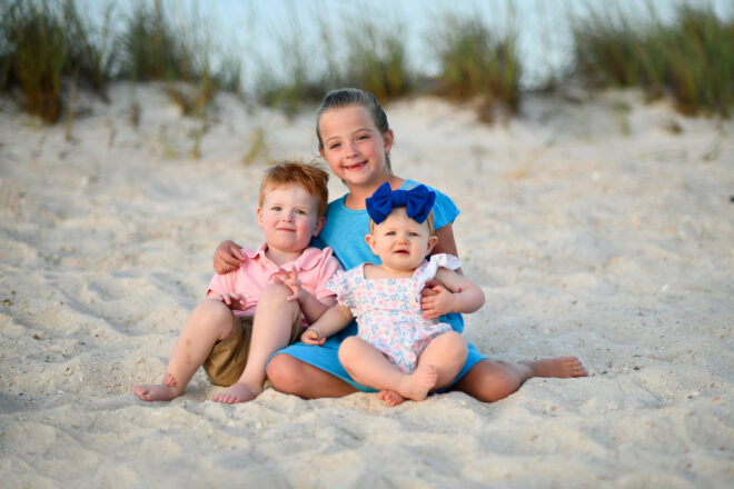 Siblings near dunes in Panama City Beach smile for our photographer.